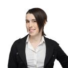 Latine person with side shave and medium-length hair in black blazer with white blouse